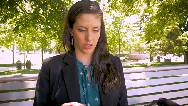 迷人的女人在公园长椅上工作的数字平板手机应用技术视频素材