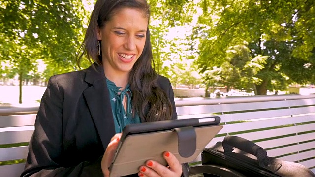 快乐微笑的女商人在公园里研究数字平板电脑技术视频素材