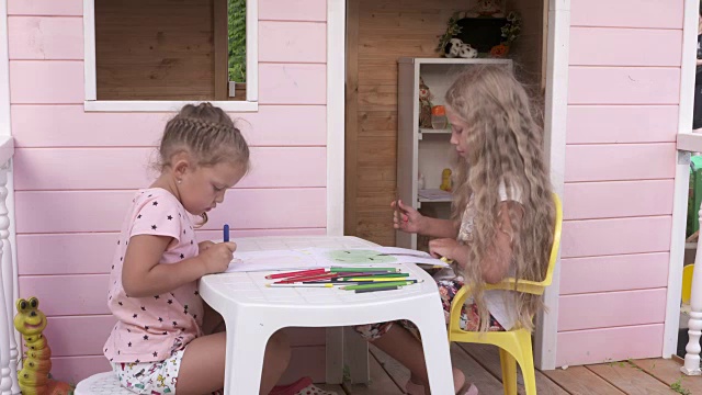 孩子们在一个粉红色木制玩具屋的阳台上玩得很开心视频素材