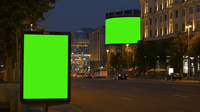 两块带有绿色屏幕的广告牌。晚上，在一条繁忙的街道上。视频素材