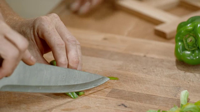 男厨师的手在木砧板上切青椒视频素材