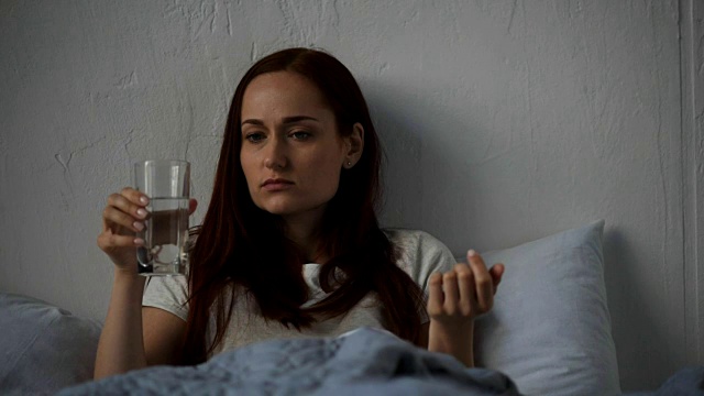 悲伤的成年女人在床上喝水视频素材