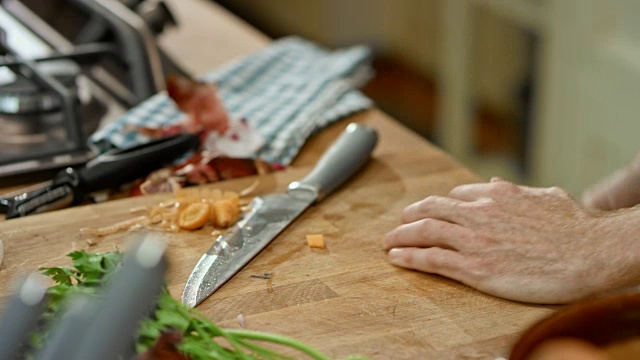 男厨师在厨房的木板上切胡萝卜并把它们放进锅里视频素材
