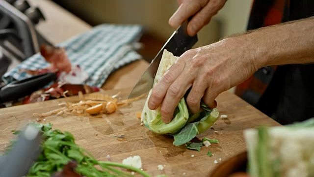 男厨师把菜花切在木板上，加到锅里的汤里视频素材