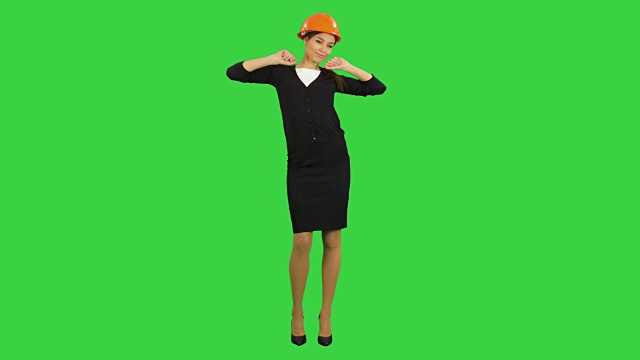 疲惫的年轻女子在安全帽打哈欠和伸展在绿色屏幕，色度钥匙视频素材
