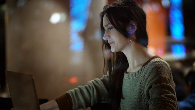 在美丽的女性使用智能手机的窗口内查看。坐在咖啡馆里用笔记本电脑工作的女人视频素材