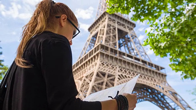 游客站在埃菲尔铁塔下，拿着巴黎地图视频素材