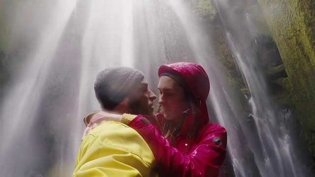 年轻快乐的旅行情侣在gopro相机上自拍。冰岛的Gljufrabui瀑布。男人和女人接吻视频素材