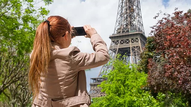 一个女人走在巴黎的街道上，拍着埃菲尔铁塔的照片视频素材