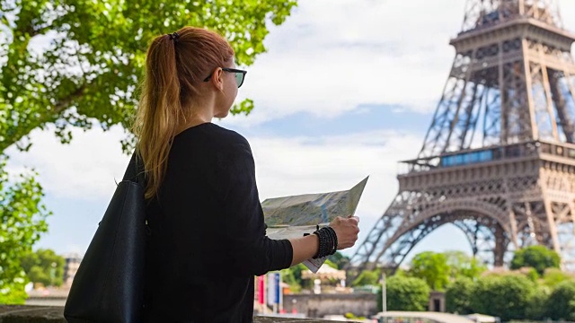 站在埃菲尔铁塔对面的女人，拿着地图探索巴黎视频素材