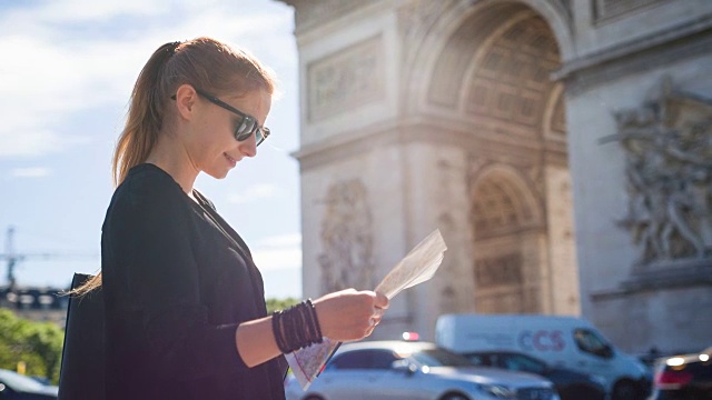 一位妇女站在著名的凯旋门前看巴黎地图视频素材