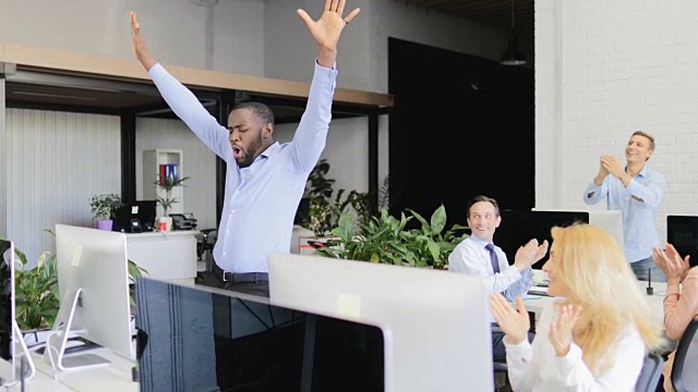 兴奋快乐的商人庆祝成功与商务人士在现代办公室鼓掌，非洲裔美国人赢家视频素材