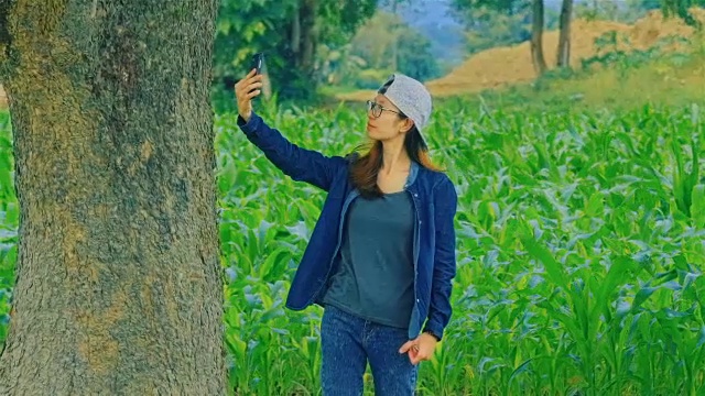 一名亚洲年轻女子在玉米地里用智能手机搜索手机信号或gps信号覆盖视频下载