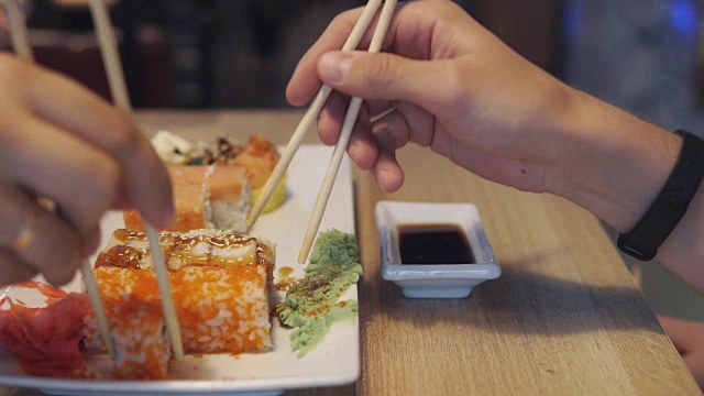 朋友们在寿司吧吃寿司蘸酱视频素材