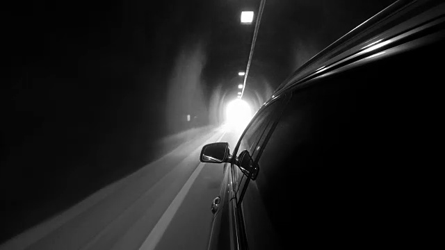 4K黑白视频显示一辆车穿过隧道最后面对着明亮的白光视频素材