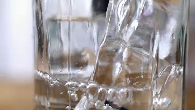 将水倒入加冰的透明玻璃杯中。视频素材