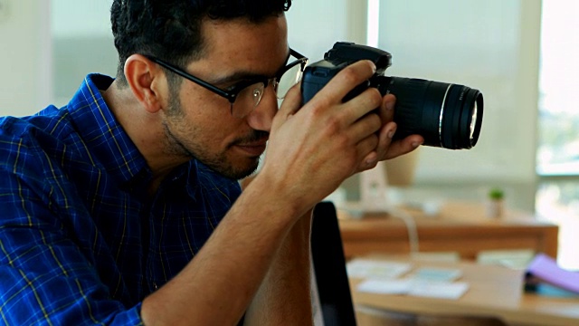 男性平面设计师在办公桌前使用数码相机视频素材