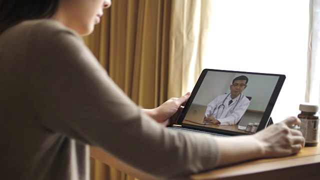 女病人在家里用数字平板电脑与资深医生交谈视频下载