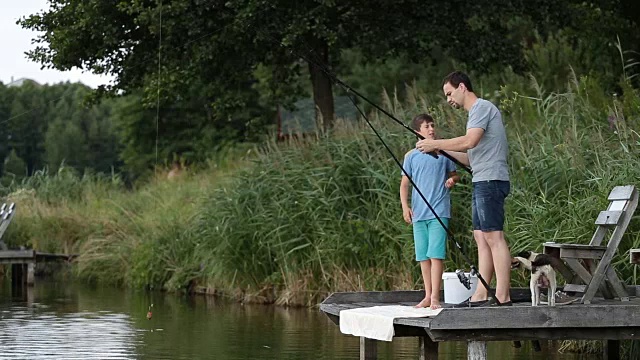 时髦的爸爸和男孩在池塘边钓鱼视频素材