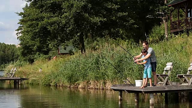 父亲教儿子在淡水塘钓鱼视频素材