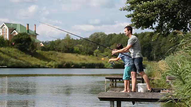 爸爸和十几岁的男孩一起在湖上钓鱼视频素材