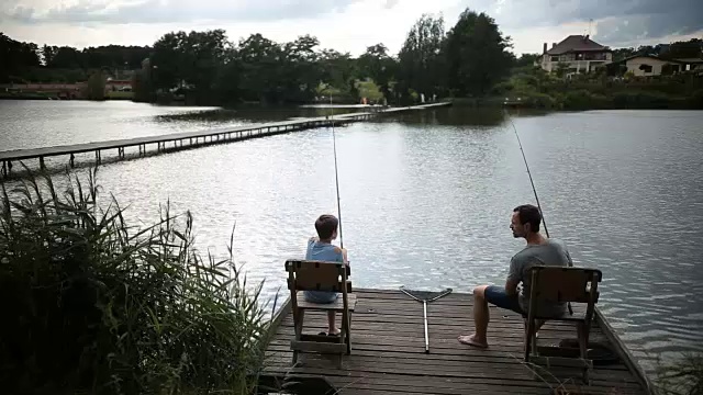 父亲和儿子在池塘里休闲钓鱼视频素材