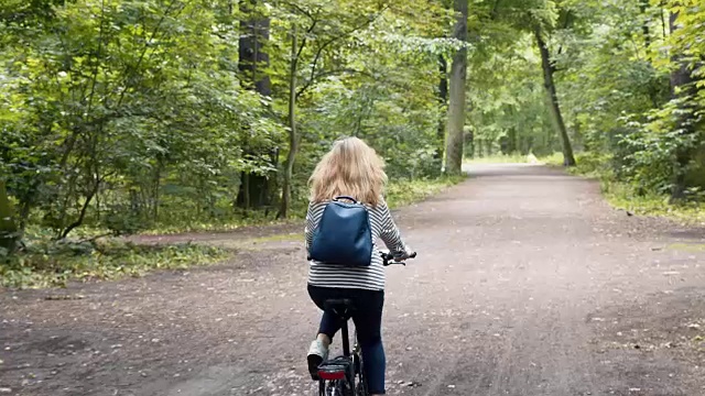 夏日公园里背着背包骑着自行车的金发美女视频下载