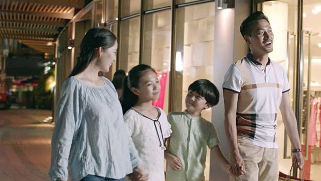 亚洲四口之家晚上在购物中心外慢镜头购物视频素材