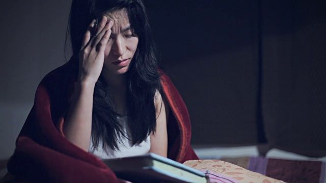 精疲力竭的亚洲大学生在家里学习到深夜。视频下载