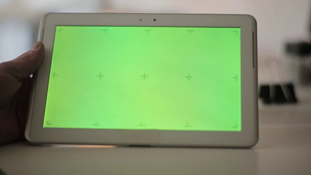 手持空白平板电脑的男子对着绿色屏幕。视频下载