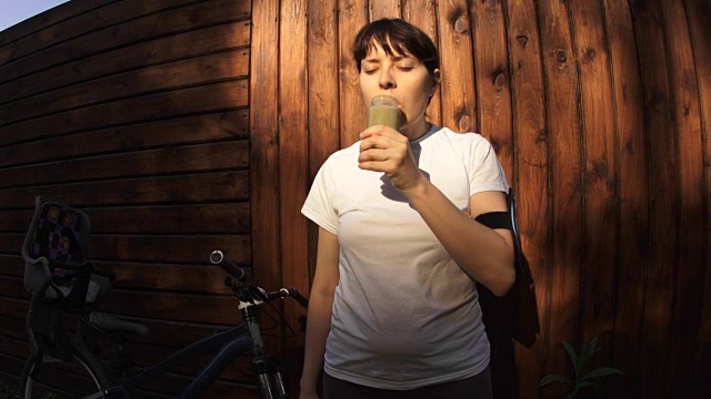 一个年轻女子在日落训练前后喝排毒奶昔。视频素材