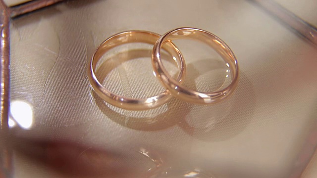 米色背景上的两个结婚戒指的特写。视频下载