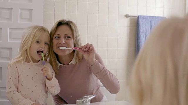 母女俩在家里对着镜子刷牙视频素材