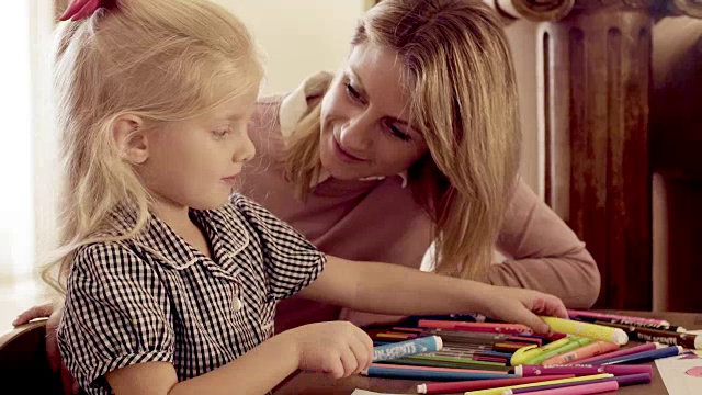母亲和女儿在家里用蜡笔在纸上画画视频素材