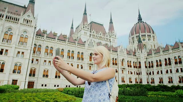 环游欧洲——一名游客在布达佩斯匈牙利议会的背景上自拍视频下载