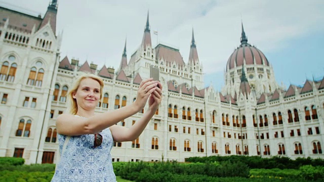 宏伟的布达佩斯。布达佩斯，一名年轻女子以匈牙利议会为背景拍摄自己的照片视频下载