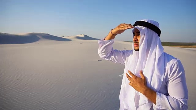 夏日里，站在广阔的沙漠中，威严的阿拉伯阿联酋酋长凝视远方，沉思视频素材