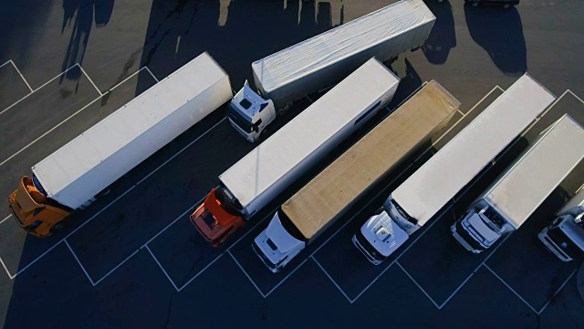 空中鸟瞰图的白色半挂车与其他卡车的货物拖车停车场在特殊停车场。视频素材