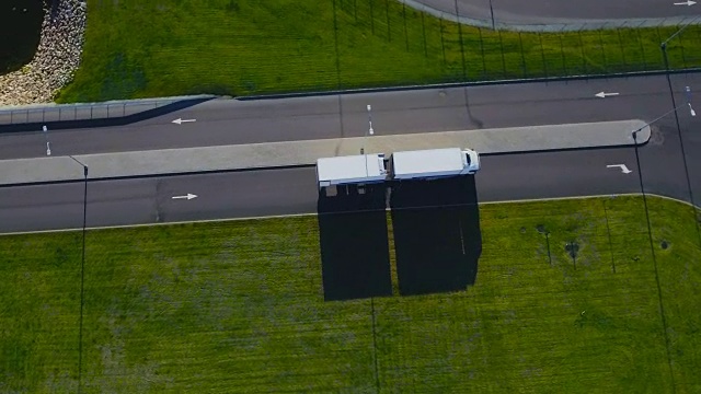 白色载货半挂车沿装卸室/工业区方向行驶的高架图。视频素材