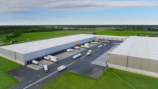 航拍工业仓库/仓库大楼/装卸区，其中有多辆货车在装卸货物。视频下载