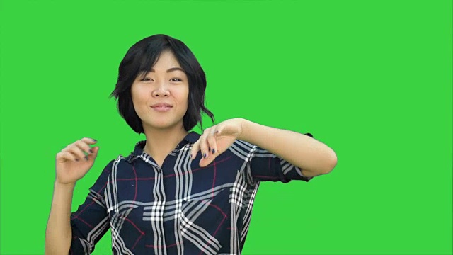 年轻的亚洲女人微笑和舞蹈在绿色屏幕上，色度钥匙视频素材