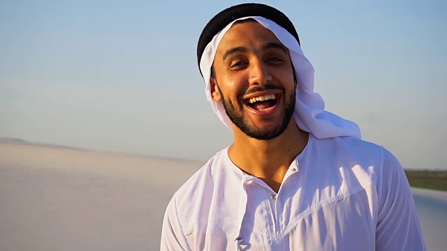 肖像美丽的笑阿联酋男性在沙漠对蓝色的天空户外视频下载