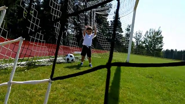 一个3岁小男孩在足球场上进球的跟踪摄像机视频素材