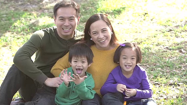 一个亚洲家庭带着两个孩子在公园里视频素材