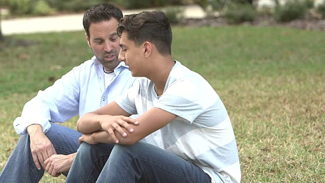 父亲和儿子坐在草坪上聊天视频素材
