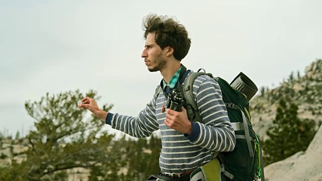 这个年轻人，潮人，徒步旅行者和背包客，在奥姆斯特德角用动作摄像机拍摄优山美地国家公园视频素材