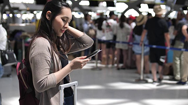 使用手机，亚洲女性在机场使用手机视频下载