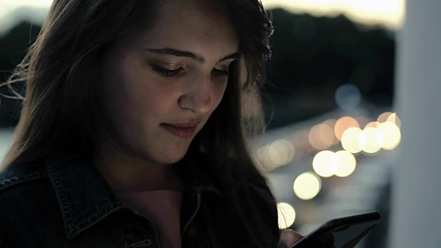 肖像年轻女子输入信息在手机上的背景傍晚城市视频素材