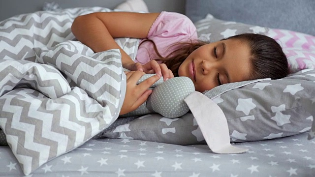 可爱的小女孩和她的玩具一起睡觉视频素材