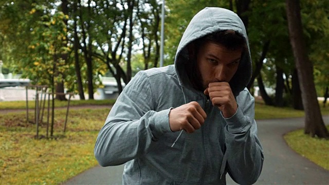 年轻的拳击手在灰色钩跑在公园和挥舞的手像拳击手视频下载